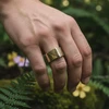 Brass geometric signet ring on hand.