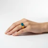 Gold ring with teal oval gemstone.