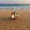 Textured silver ring on sandy beach.