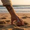 Hand in sand wearing silver ring.