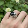 Black stone signet ring with silver, textured band.