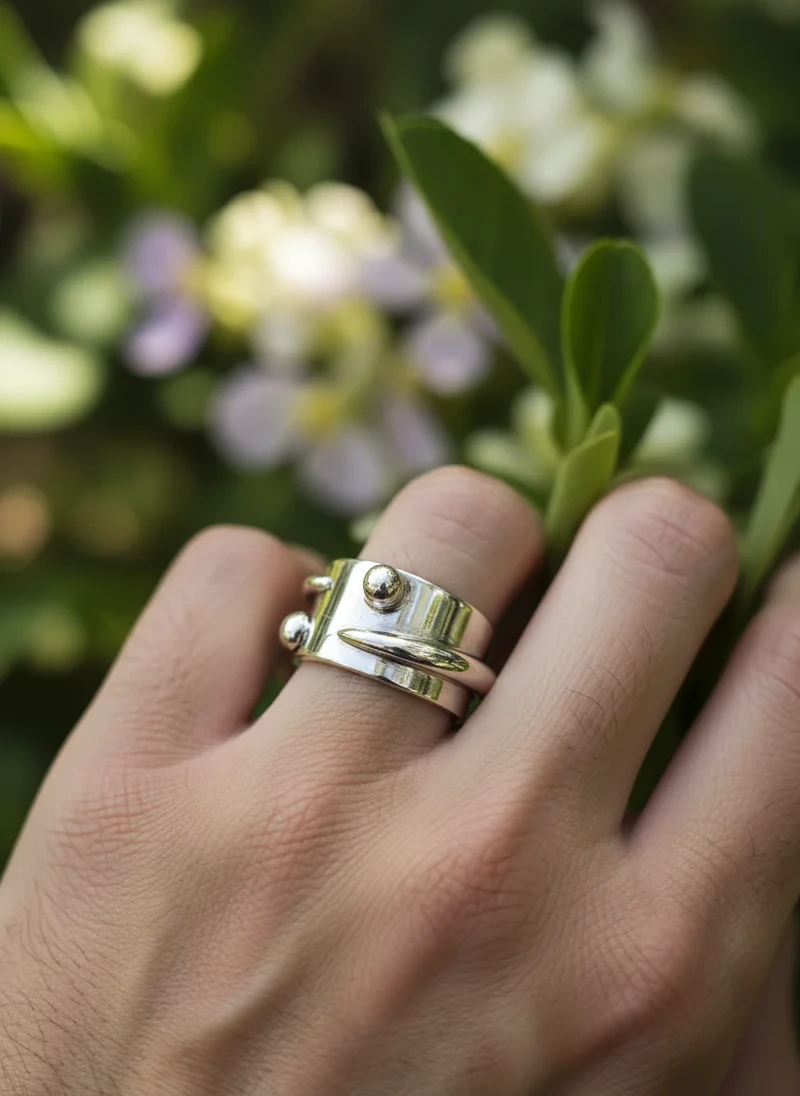 Silver statement ring with textured band and metallic spheres.