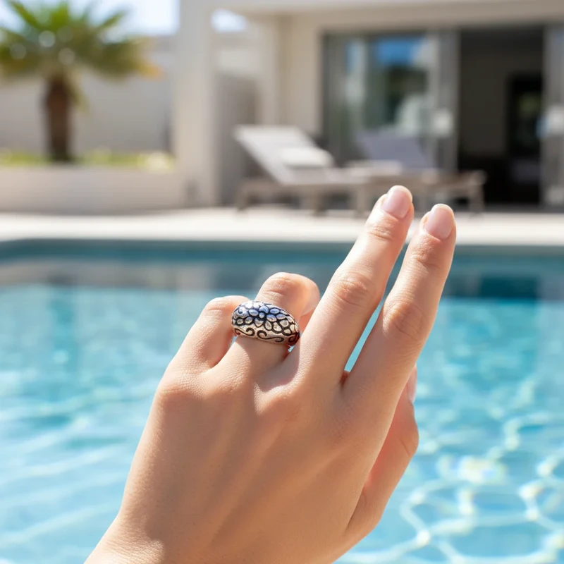 Silver ring with floral design, worn on finger.