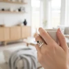 Hand holding mug, showcasing silver crown ring with black stone.