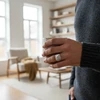 Man's hand wearing silver signet ring, holding a mug.