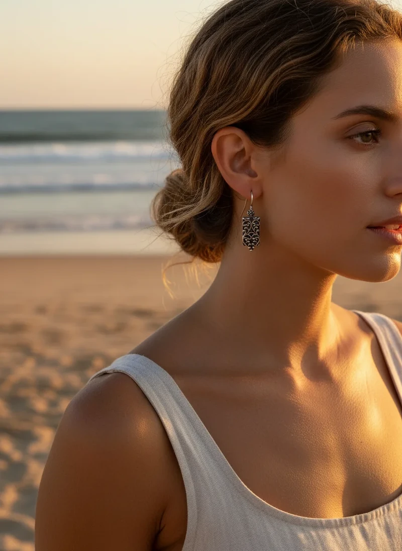 Woman wearing ornate silver heart earrings.