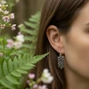 Silver filigree earrings on model.