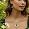 Woman wearing dark green gemstone necklace & earrings.