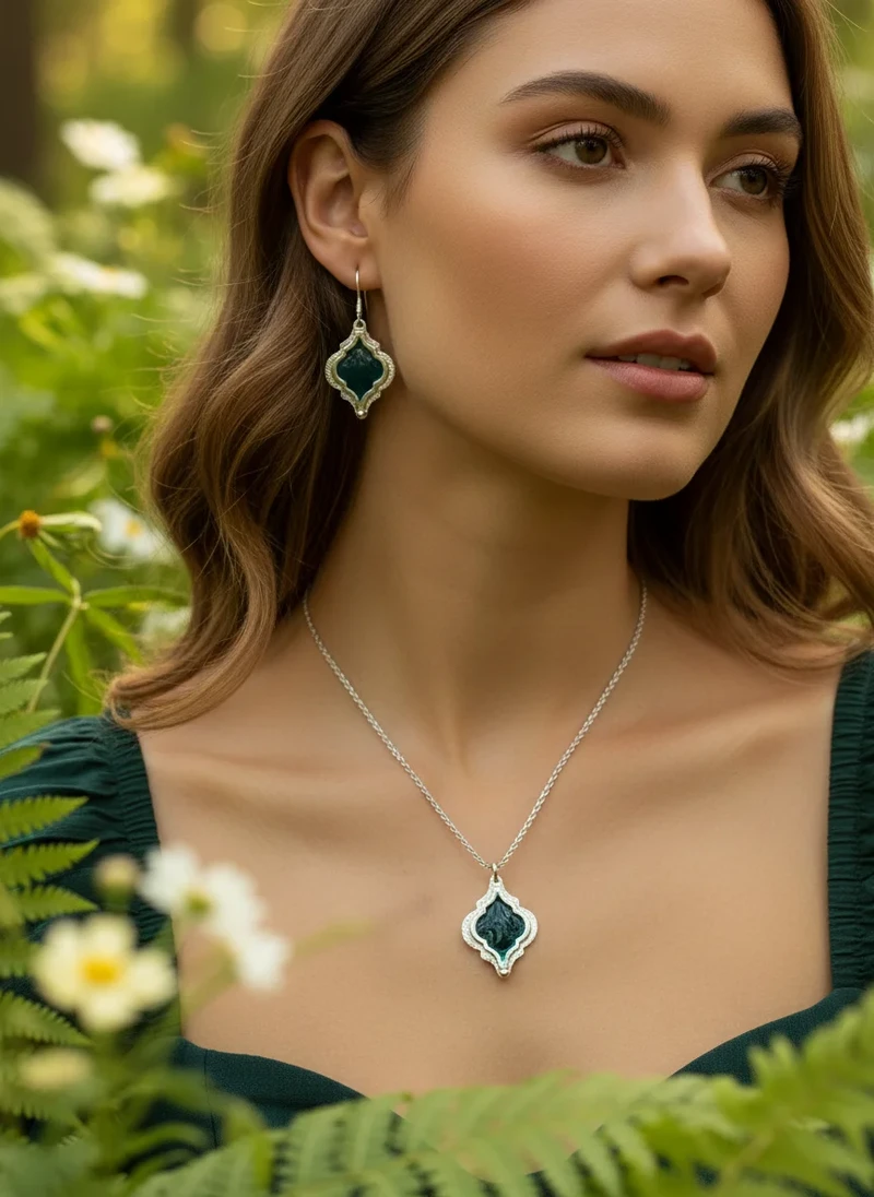 Woman wearing dark green gemstone necklace & earrings.