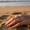 Silver pearl ring on hand in sand.