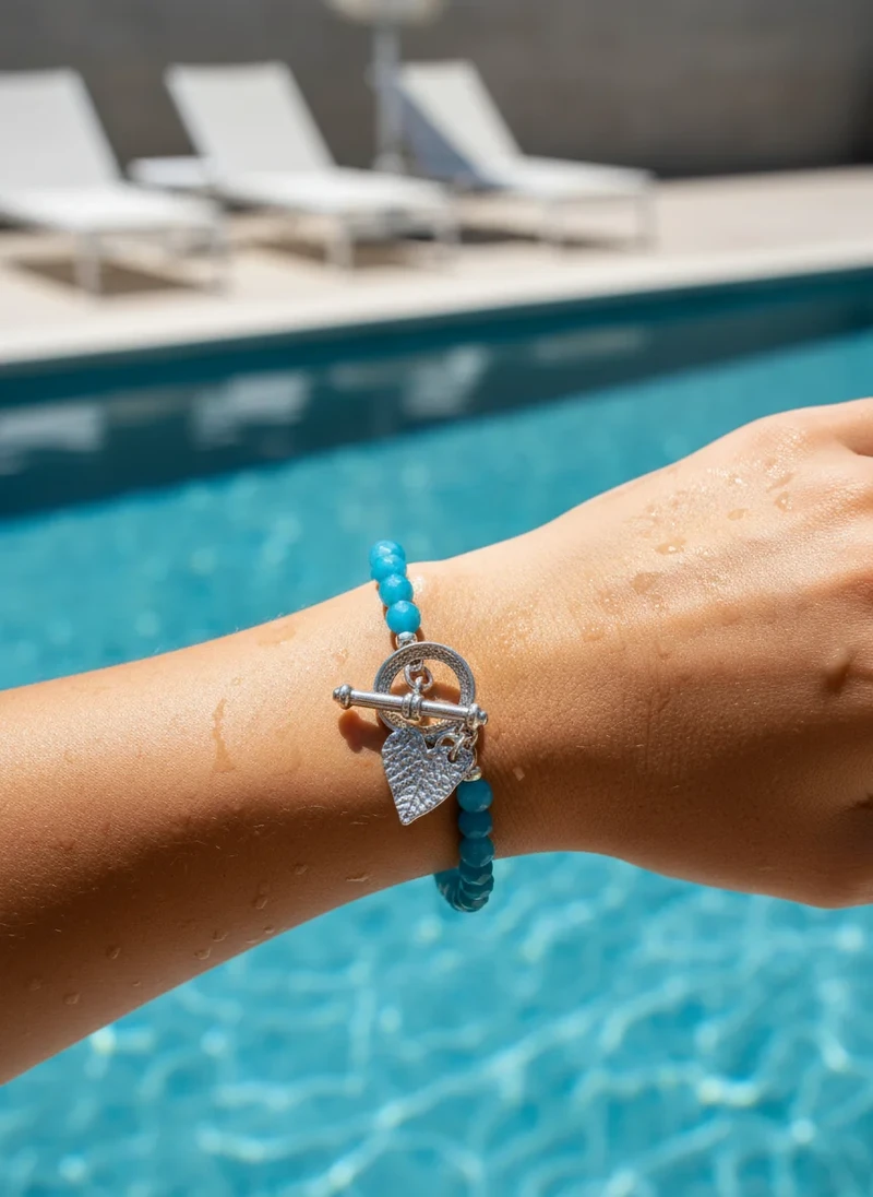 Teal beaded bracelet with silver heart charm.