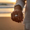 Silver ribbed band ring on hand at sunset.