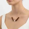 Gold chain necklace with brown wood and white shell beads.