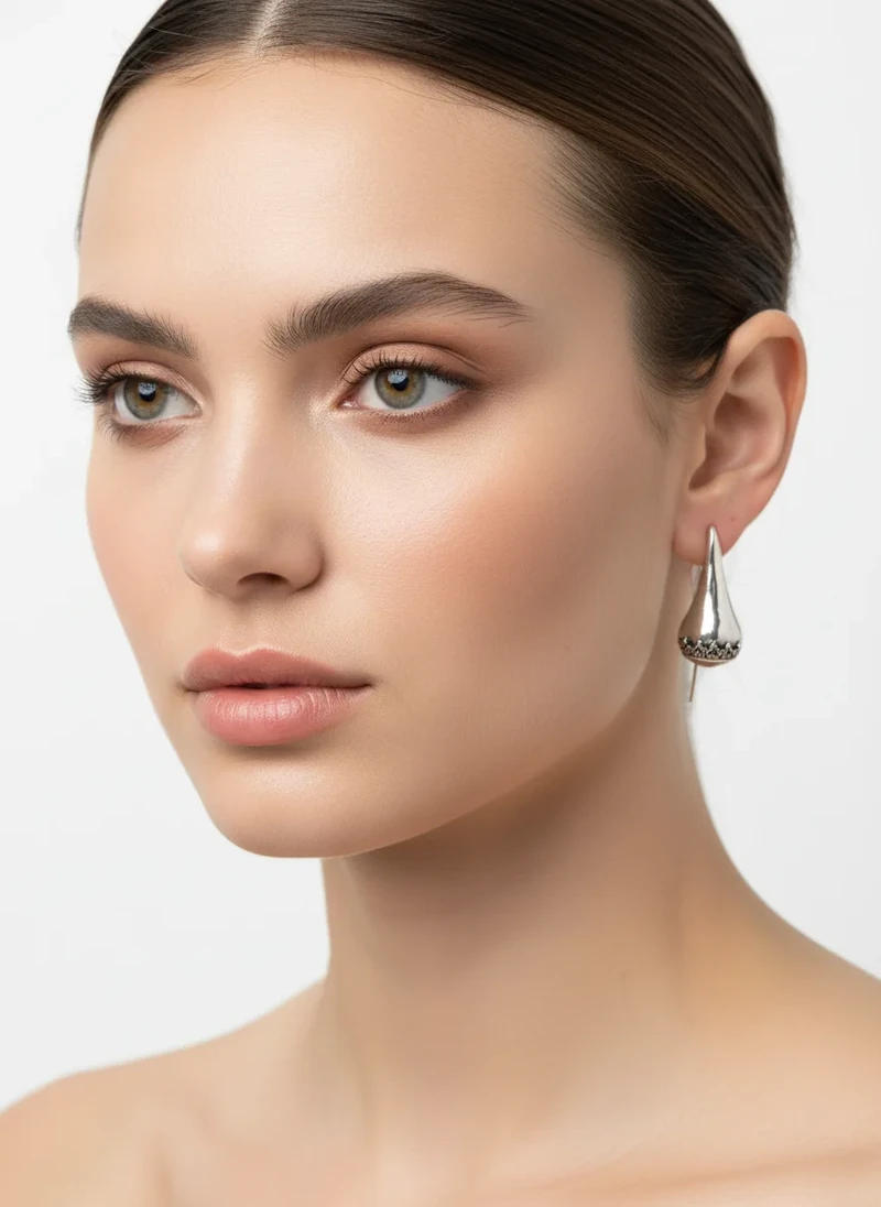 Woman wearing silver teardrop earrings.