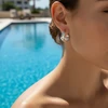 Woman's ear wearing silver cutout hoop earrings.