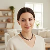 Woman wearing dark pearl necklace with silver charms.