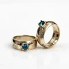 Pair of gold rings with blue gemstones and floral engraving.