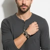 Man wearing layered beaded bracelets.