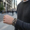 Man's wrist wearing stacked beaded bracelets and anchor charm.